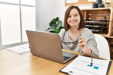 Frau mit Down-Syndrom arbeitet am Laptop