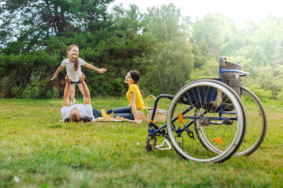 Frau im Rollstuhl mit Familie im Park