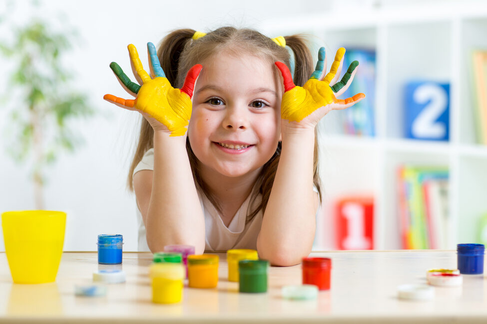 Kindergartenkind mit farbig bemalten Fingern
