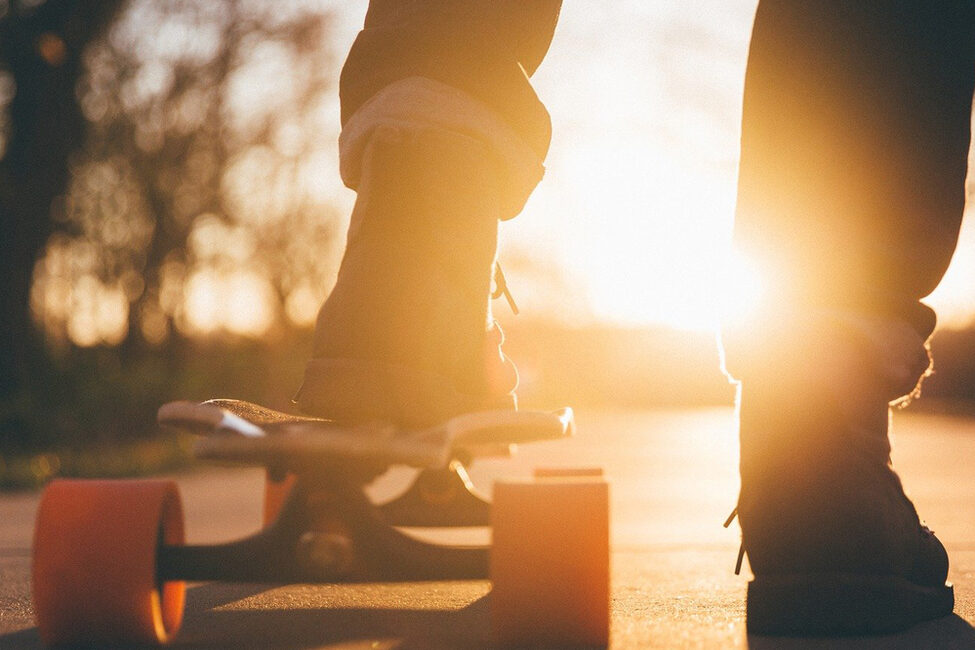 Füße auf einem Skateboard im Gegenlicht