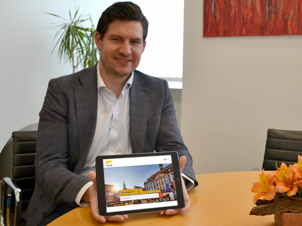 OB Dominik Sauerteig hält ein Tablet, das die neue Website zeigt.