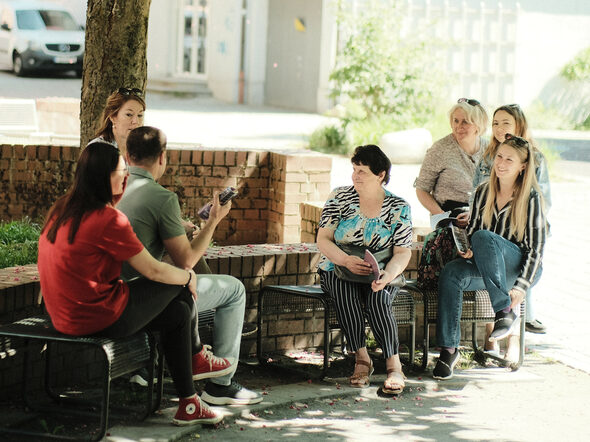 Eine Gruppe Menschen sitzt im Park und unterhält sich.