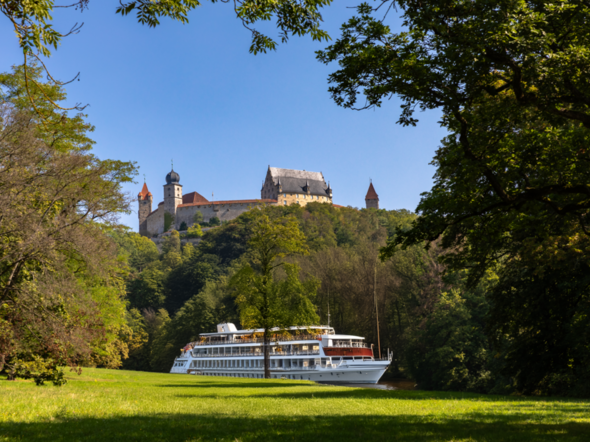 KI generiertes Bild, das ein Flusskreuzfahrtschiff vor der Veste Coburg zeigt