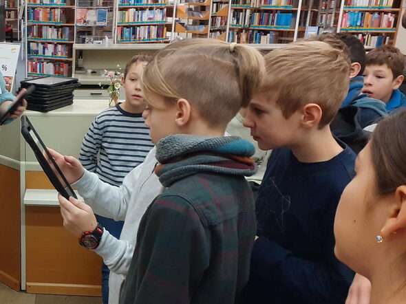 Schüler*innen des Gymnasiums Ernestinum entdecken die Stadtbücherei mit einem iPad.