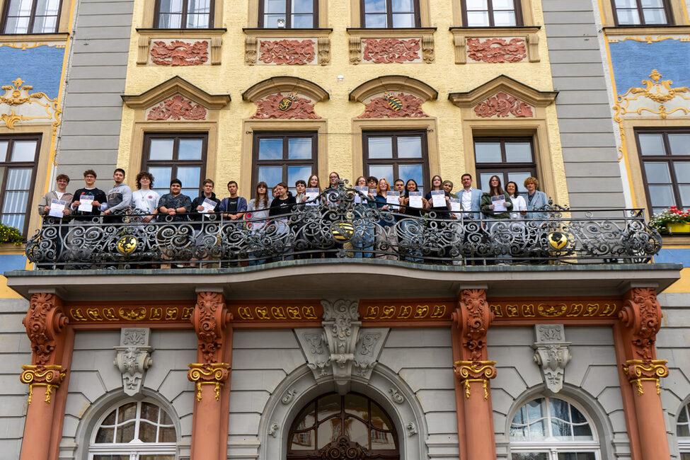 Die Schulklasse mit Urkunden auf dem Rathausbalkon