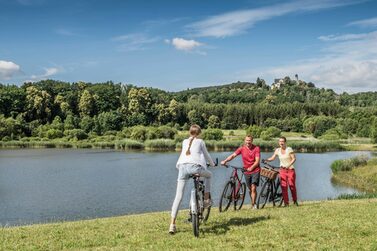 Eine Gruppe von drei Radfahrenden auf einer Wiese am Goldbergsee