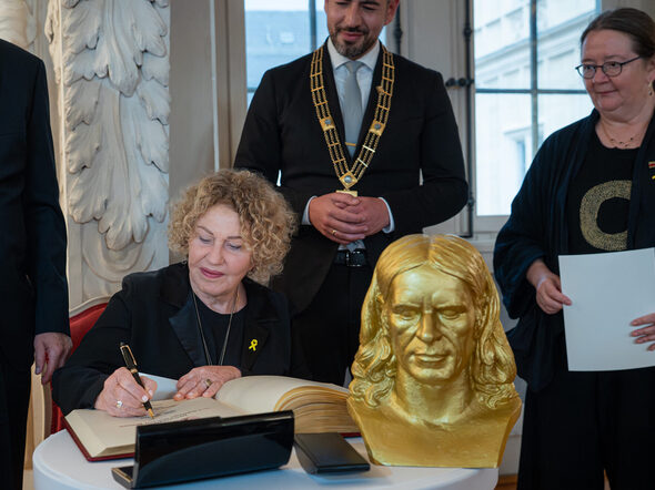 Aghi Mishol, Preisträgerin des Rückertpreises 2025 trägt sich ins Goldene Buch der Stadt ein.