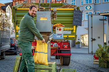 Ein Händler füllt Kartoffeln von seinem Traktor in einen Kartoffelsack.