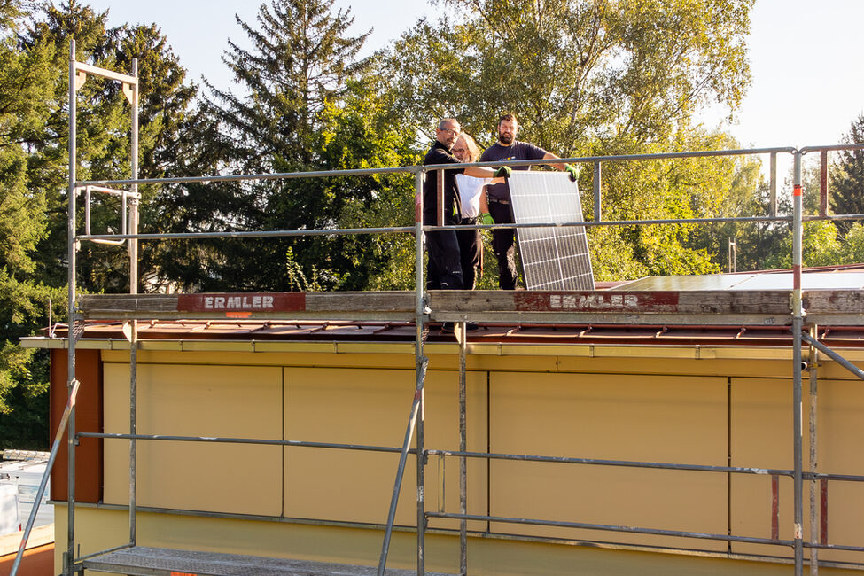 Arbeiter montieren die neue PV-Anlage auf dem Dach der Rolf-Forkel-Halle in Lützelbuch.