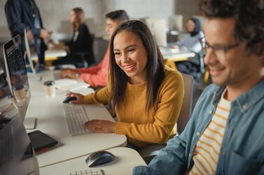 Ein junger Mann und eine junge Frau sitzen vor ihren Computern