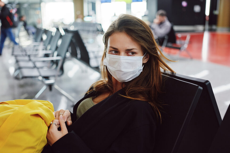 Reisende mit Maske am Flughafen