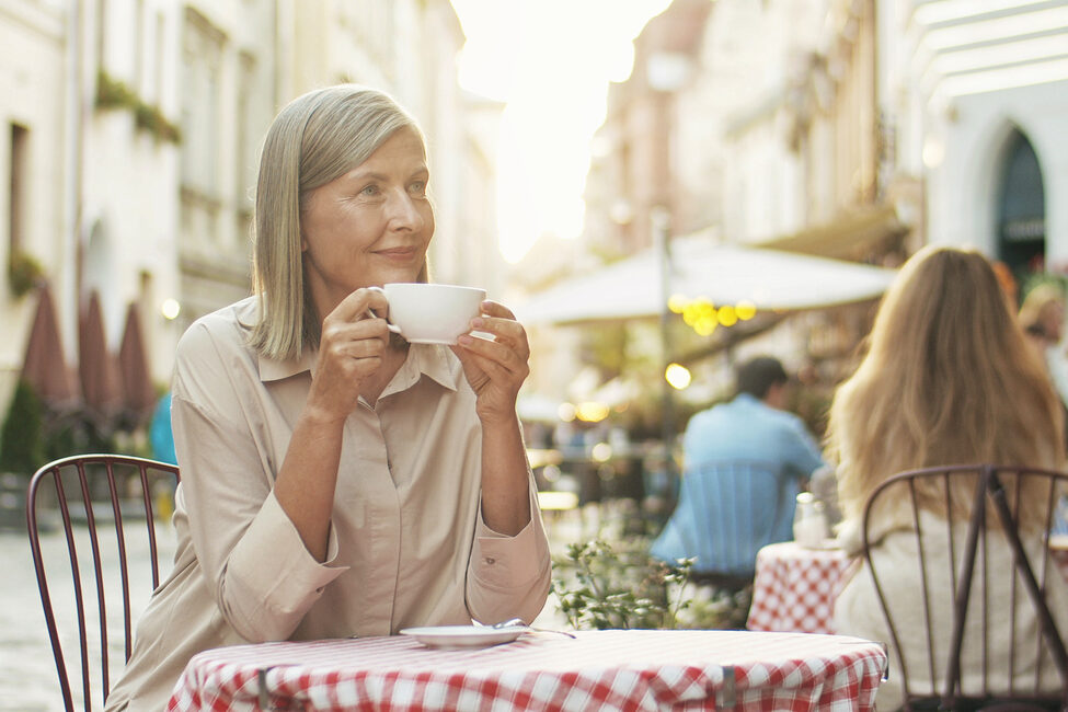 Ältere Frau genießt einen Kaffee in einem Straßencafé