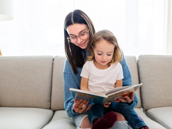 A,Happy,Kid,Sitting,On,Sofa,With,Babysitter,Holding,Book