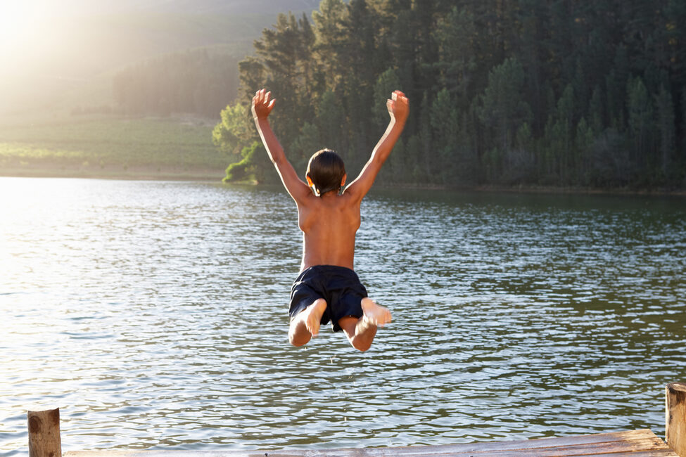 Junge springt zum Schwimmen in den See