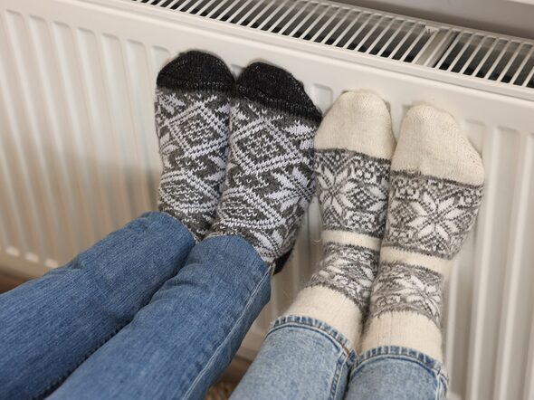 Couple,Warming,Feet,Near,Heating,Radiator,At,Home,,Closeup