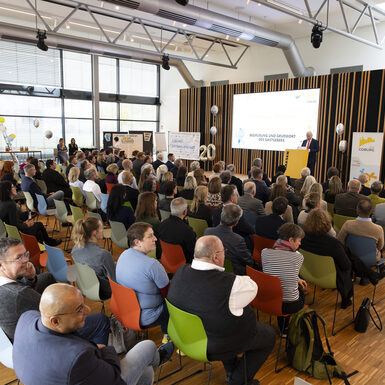 Publikum sitzend auf Stühlen vor der Bühne.