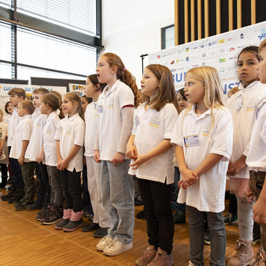 Schülerinnen und Schüler stehen zusammen und singen ein Lied.
