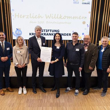 Mehrere Personen stehen in einer Reihe und halten eine Urkunde.