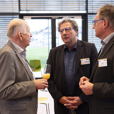 Drei Männer stehen zusammen und unterhalten sich.