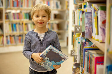 Kind mit Buch in der Hand in einer Buchhandlung