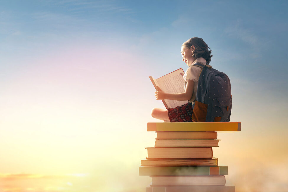 Kind sitzt auf einem Bücherstapel