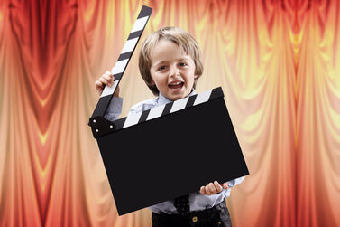 Kind mit Filmklappe vor Theatervorhang