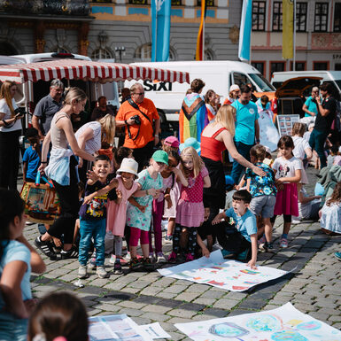 Eine Gruppe von Kindern steht zusammen rund um selbstgestaltete Plakate zum Thema Toleranz
