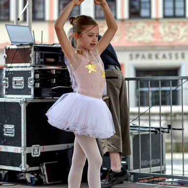 Ein Mädchen in Balletkleidung steht auf der Bühne und tanzt.