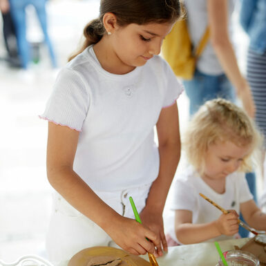 Ein Mädchen malt mit Pinsel und Farbe.
