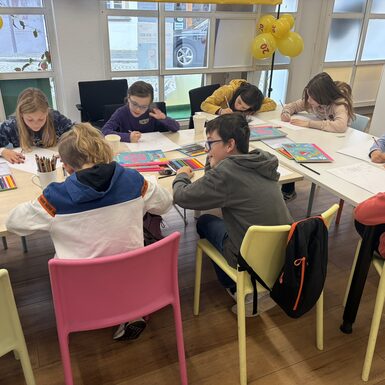 Kinder sitzen an einem Tisch und malen.