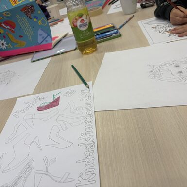 Zeichnungen und Stifte liegen auf einem Tisch.