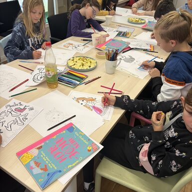 Kinder sitzen an einem Tisch und zeichnen.