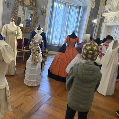 Kinder stehen vor Kostümen von früher und betrachten diese.