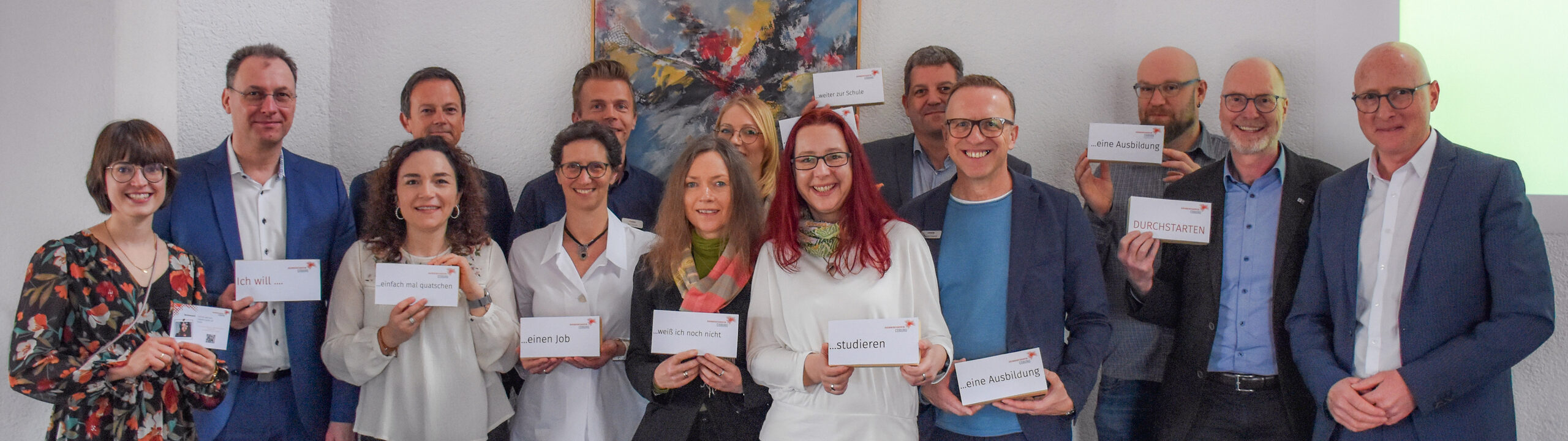 Das Foto zeigt die Mitglieder des Netzwerkes der Jugendberufsagentur in der Region Coburg. Zu sehen sind die 10 Partnerinstitutionen mit ihren Mitgliedern des Netzwerkes. Alle halten Schilder mit den Themenbereichen der Homepage der Jugendberufsagentru in die Kamera.