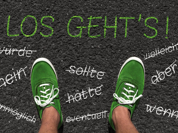 Zwei Fü0e mit grünen Schuhen stehen auf dem Asphalt. Wörter wie nein, aber, wenn in weißer Schrift auf grauem Asphalt sind durch gestrichen.