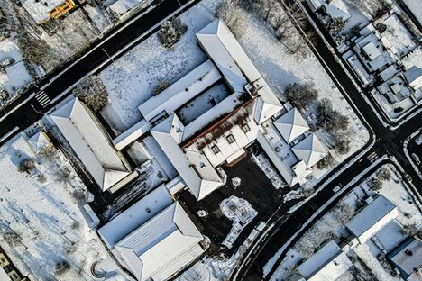 Das Foto zeigt die Luftaufnahme der Mittelschule am Moos im Winter mit schneebedeckten Dächern